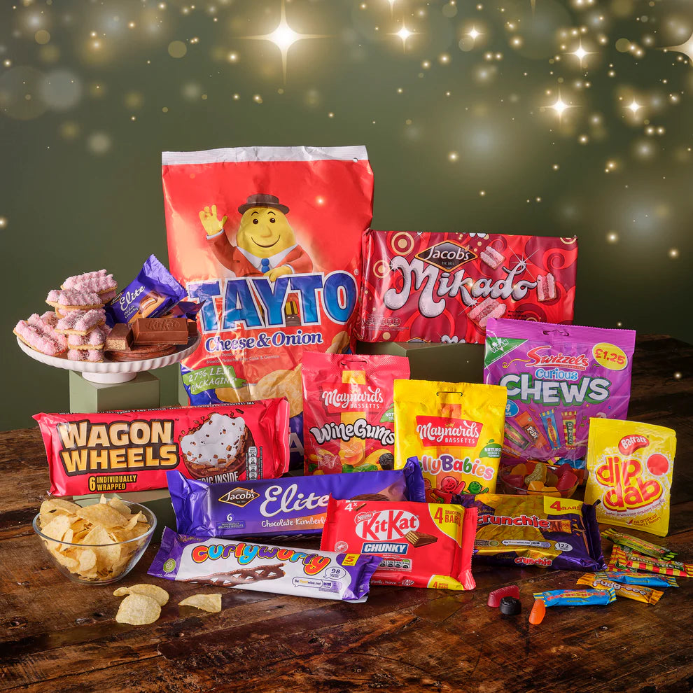 Assorted Irish snacks, Tayto, Maynards jellies, wagon wheels, and Jacobs biscuits  on a wooden table with a festive background
