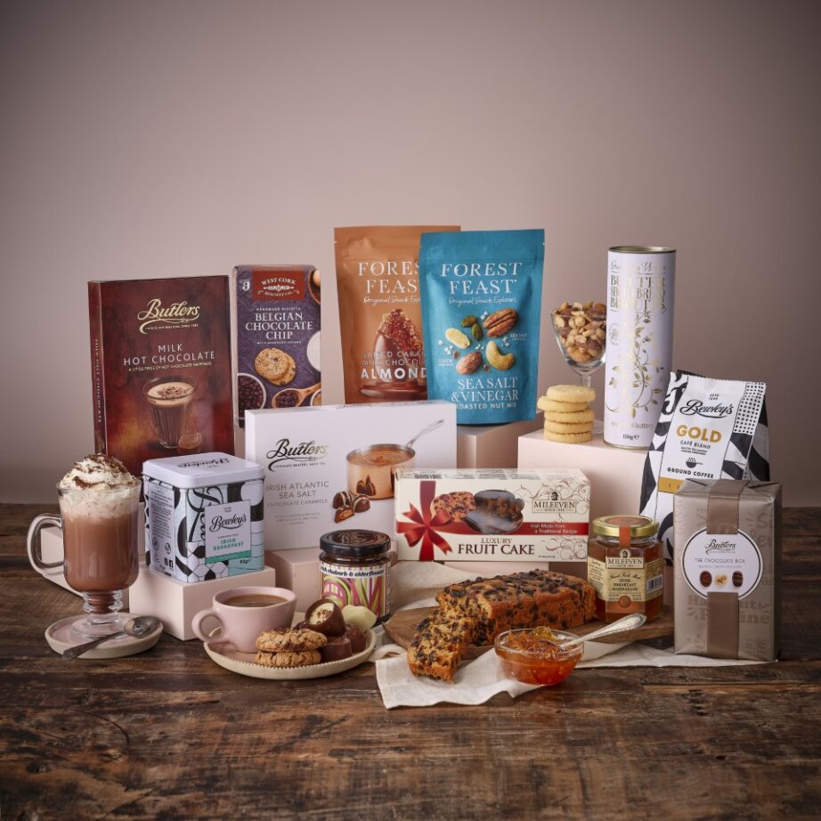 Assorted food and drink hamper with chocolates cookies tea and snacks displayed on a wooden table