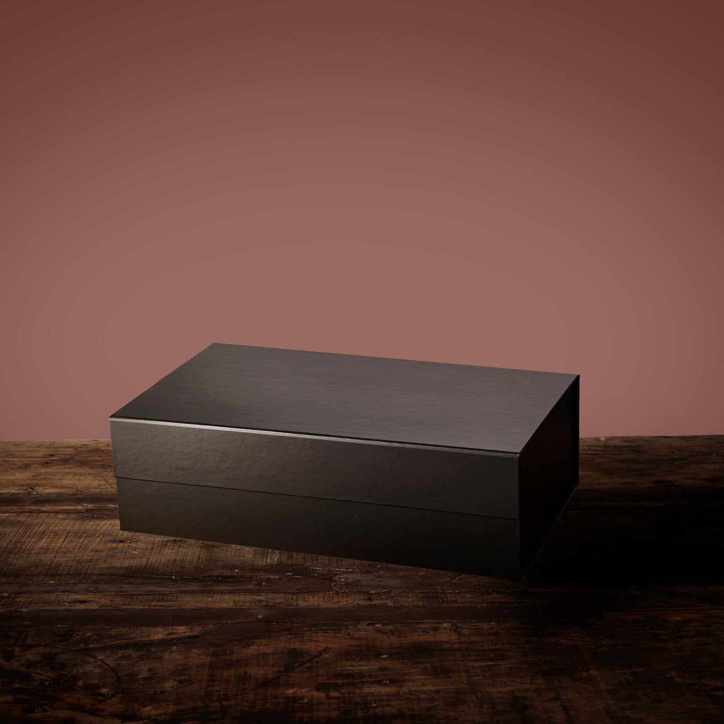Mother’s Day Relax and Unwind Hamper shown as a sleek matte black gift box against a pink backdrop.