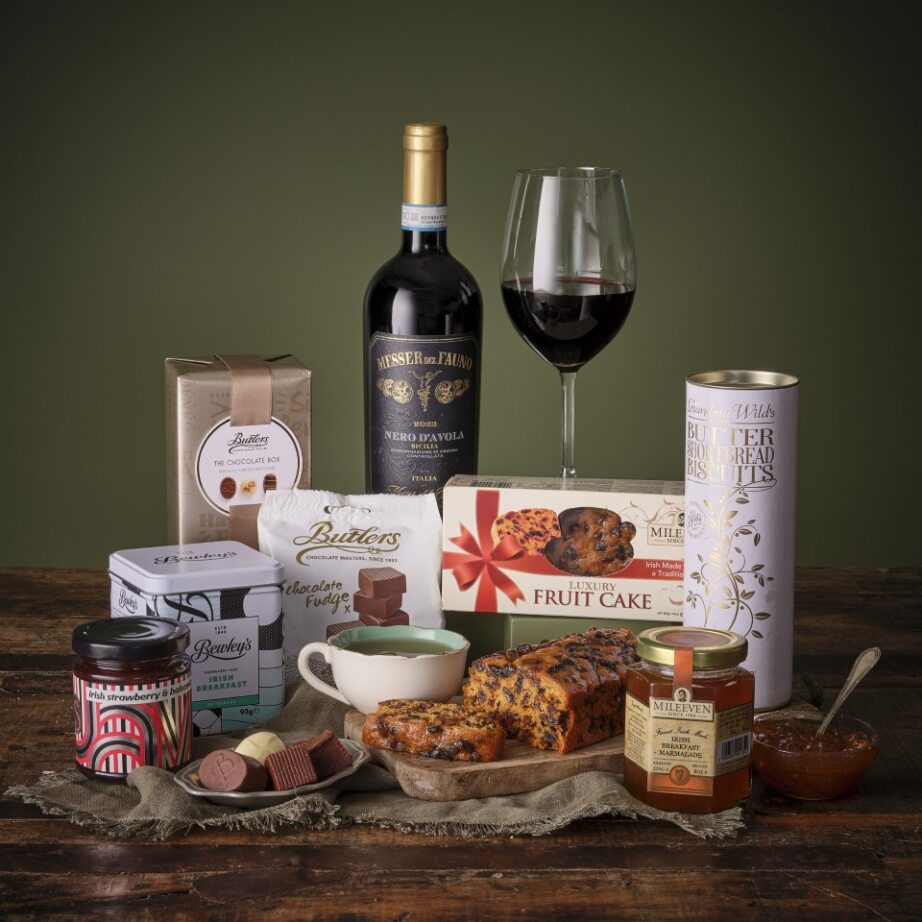 The Thank You Hamper with red wine bottle, wine glass, and assorted chocolates and biscuits on a wooden surface.