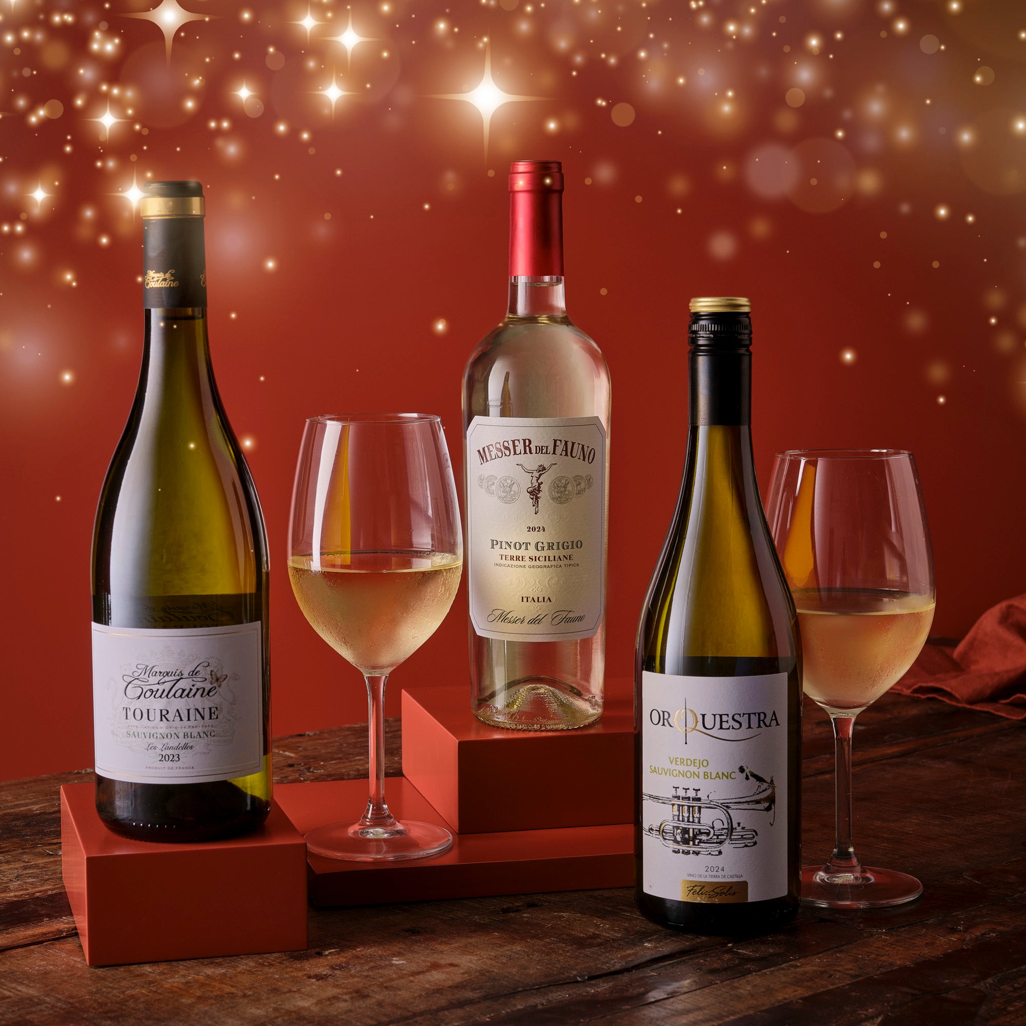 Three wine bottles with glasses on a wooden surface against a warm, glowing background