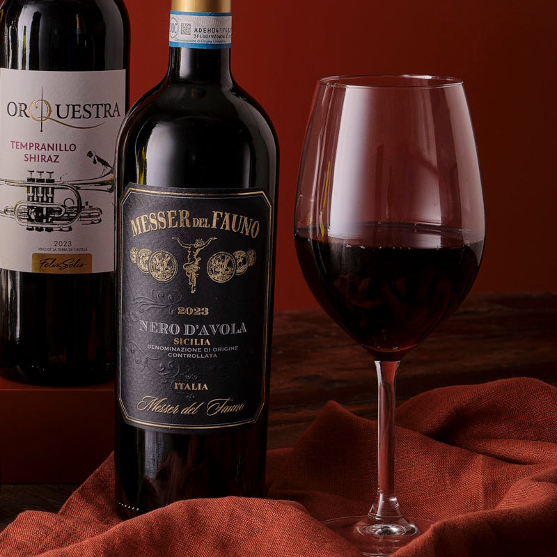 Wine bottle labeled 'Messer del Fauno' with a glass of red wine on a red cloth.