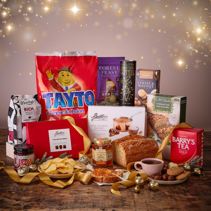 Assorted food products including Tayto, Barry's Tea, and other snacks on a wooden table with a festive background.