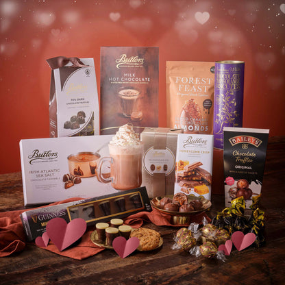 Assorted chocolate hamper featuring truffles bars and gift boxes arranged on a wooden table.