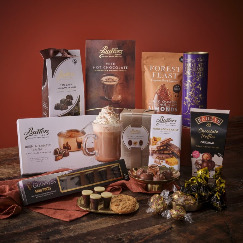 Assorted chocolate hampers and boxes arranged on a wooden surface with a red backdrop.