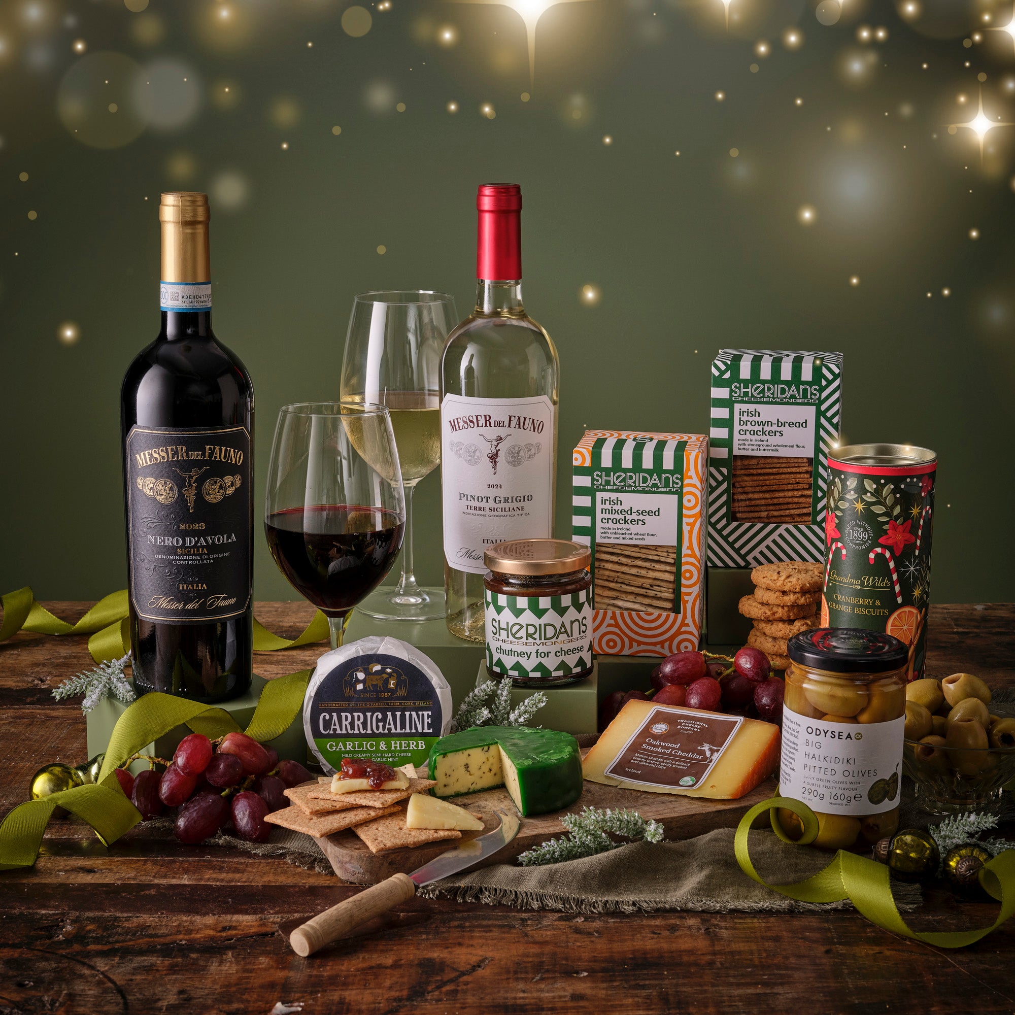 Red & White Wine bottles, glasses, and assorted crackers and cheese snacks on a wooden table with a festive background.