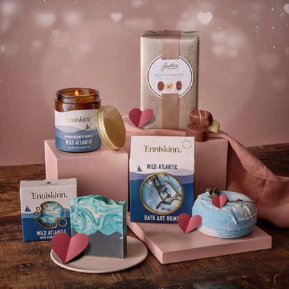 Enniskinn romantic escape gift set with scented candle bath products and blue marbled soap on a pink display.