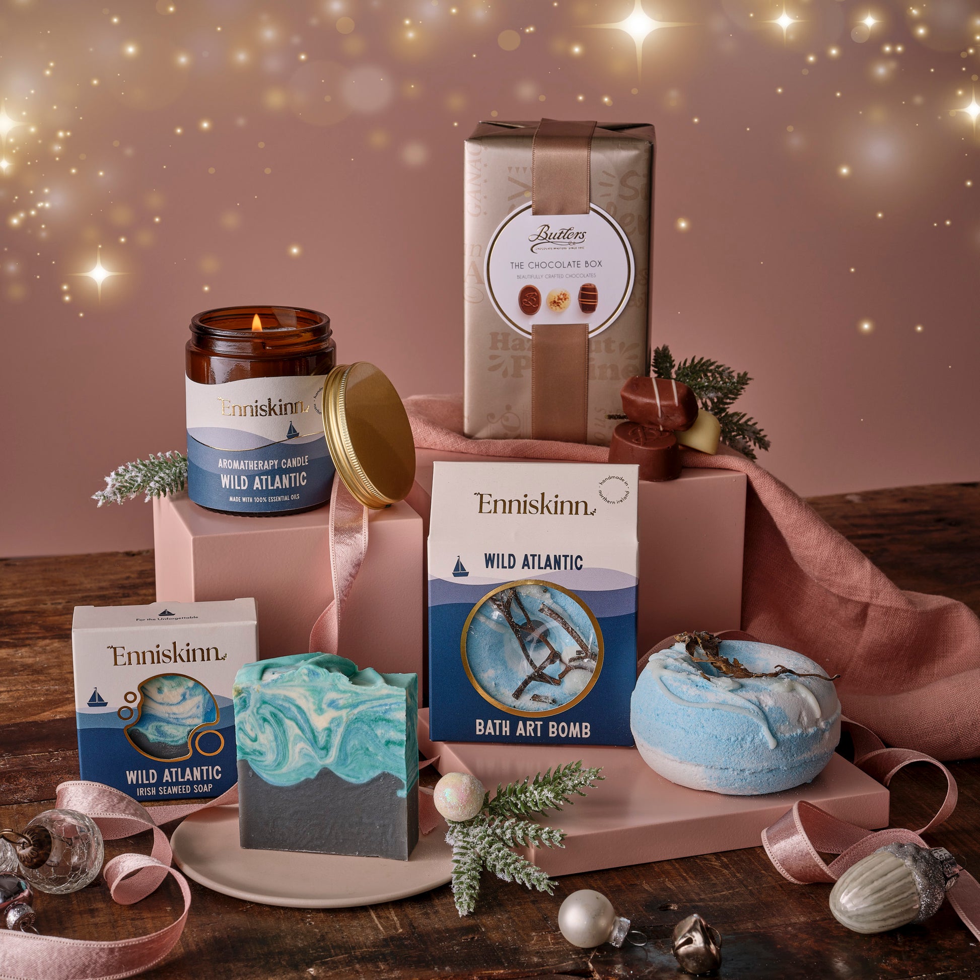 Enniskinn, candle, soap, Butlers chocolates and decorative items on a wooden surface with a warm glow.