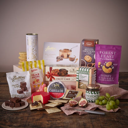 Assorted gourmet snacks gift hamper with cookies chocolates tea and treats arranged on a wooden surface