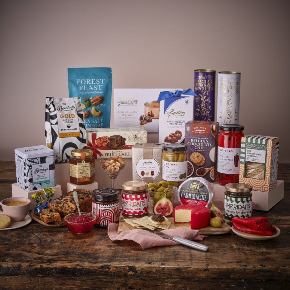 Gourmet Selection Hamper assortment featuring a white gift box with blue ribbon surrounded by chocolates biscuits and jars.