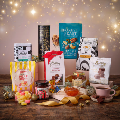 Assorted Sweets, Butlers chocolates, Bewleys Tea and decorative items on a wooden board with a festive background