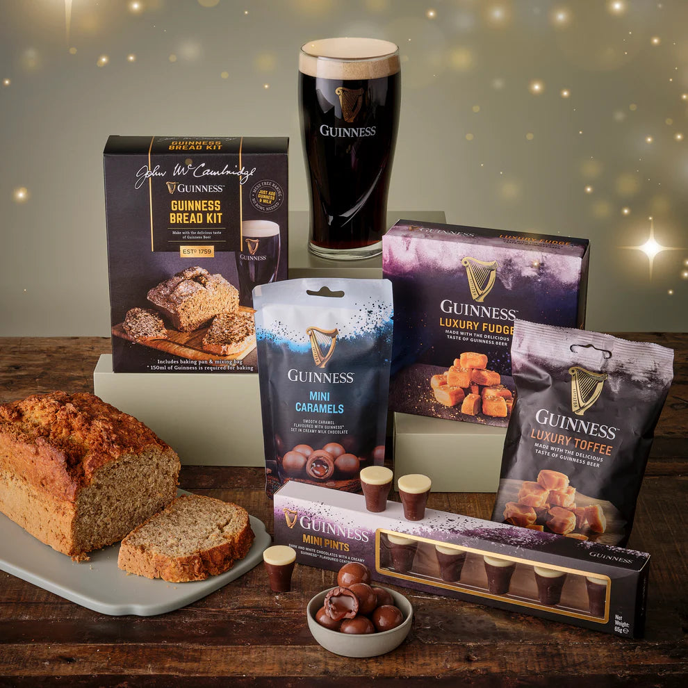 Collection of Guinness-themed food products including bread, fudge, toffee, and caramels on a wooden table.