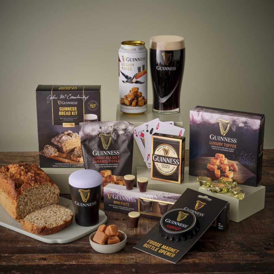 Guinness snacks and gifts hamper with bread, sea salt caramel fudge, luxury toffee and chocolates arranged on a wooden table.
