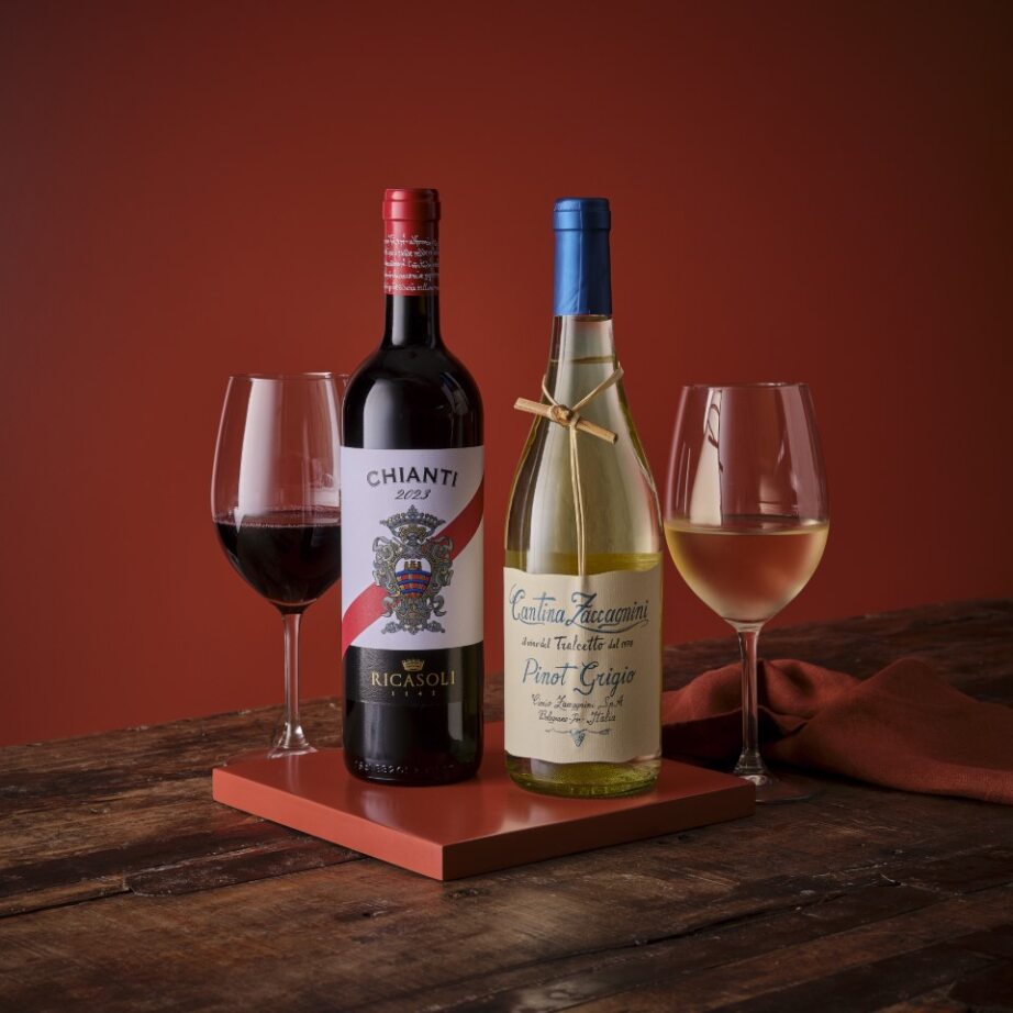 Two wine bottles with glasses on a wooden surface against a warm, glowing background