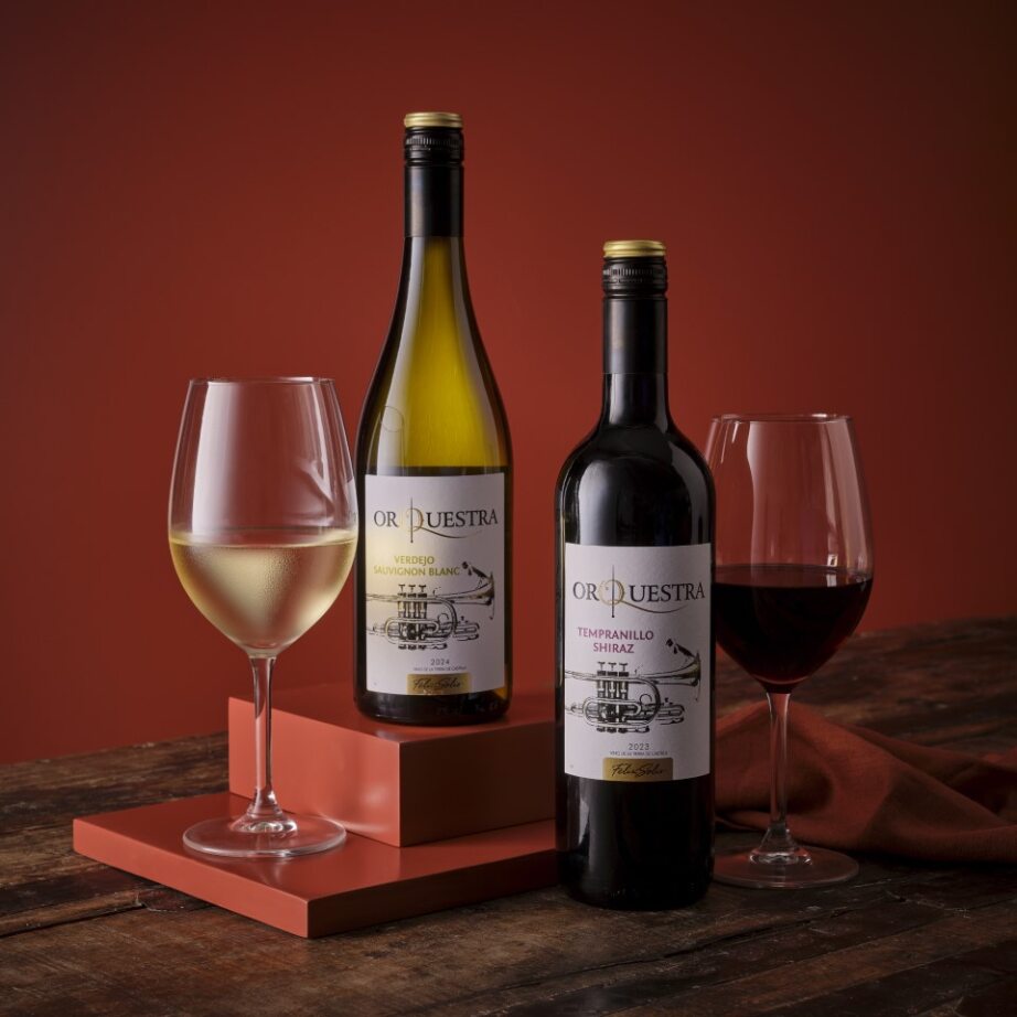 Orquestra two bottle wine set with white Verdejo Sauvignon Blanc and red Tempranillo Shiraz beside glasses on orange blocks.