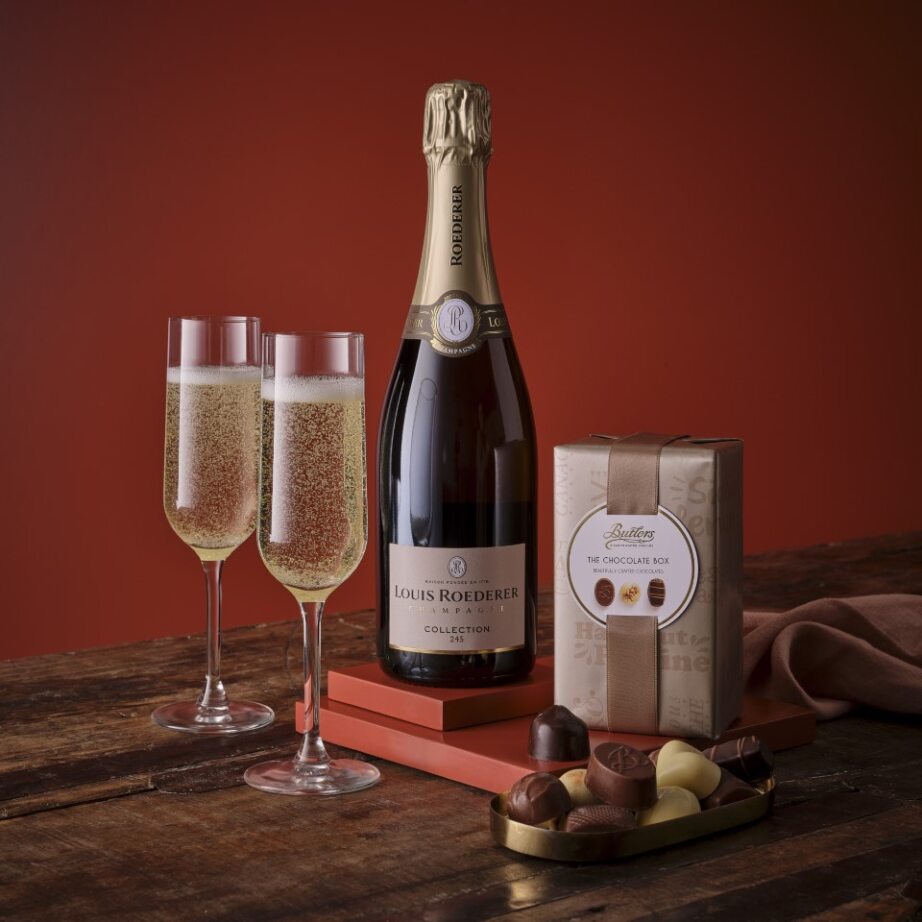 Premium Champagne and chocolate set with a Louis Roederer bottle, two fluted glasses, a chocolate box, and chocolates on a wooden table