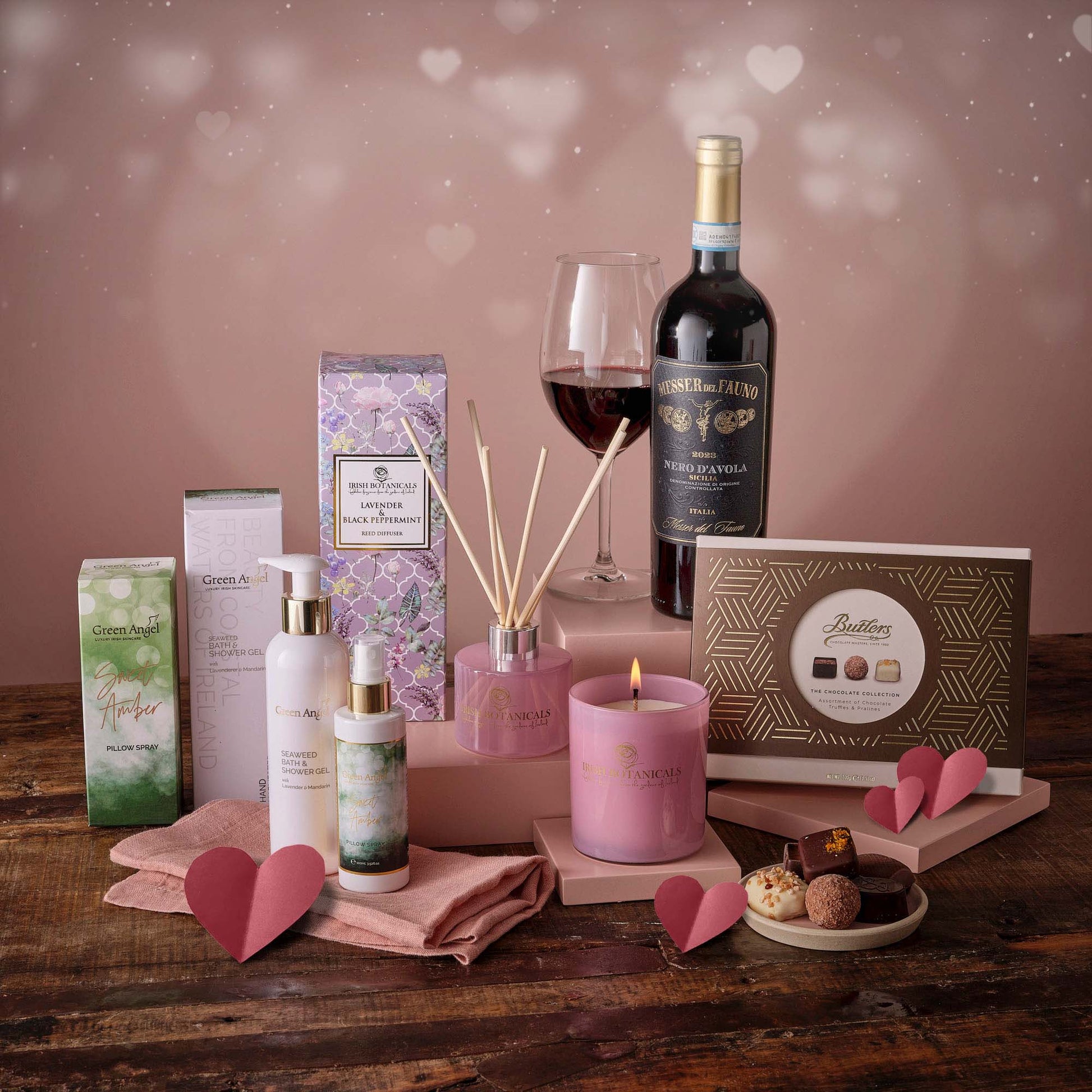 The Valentine Pamper Hamper with wine lavender diffuser and bath products among pastel packaging.