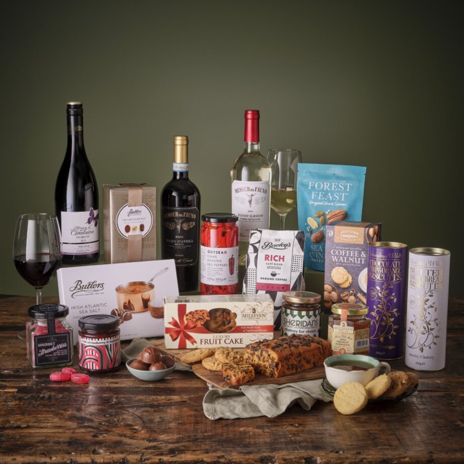 Lavish five star hamper featuring wine coffee biscuits jams and a fruit cake arranged on a wooden table