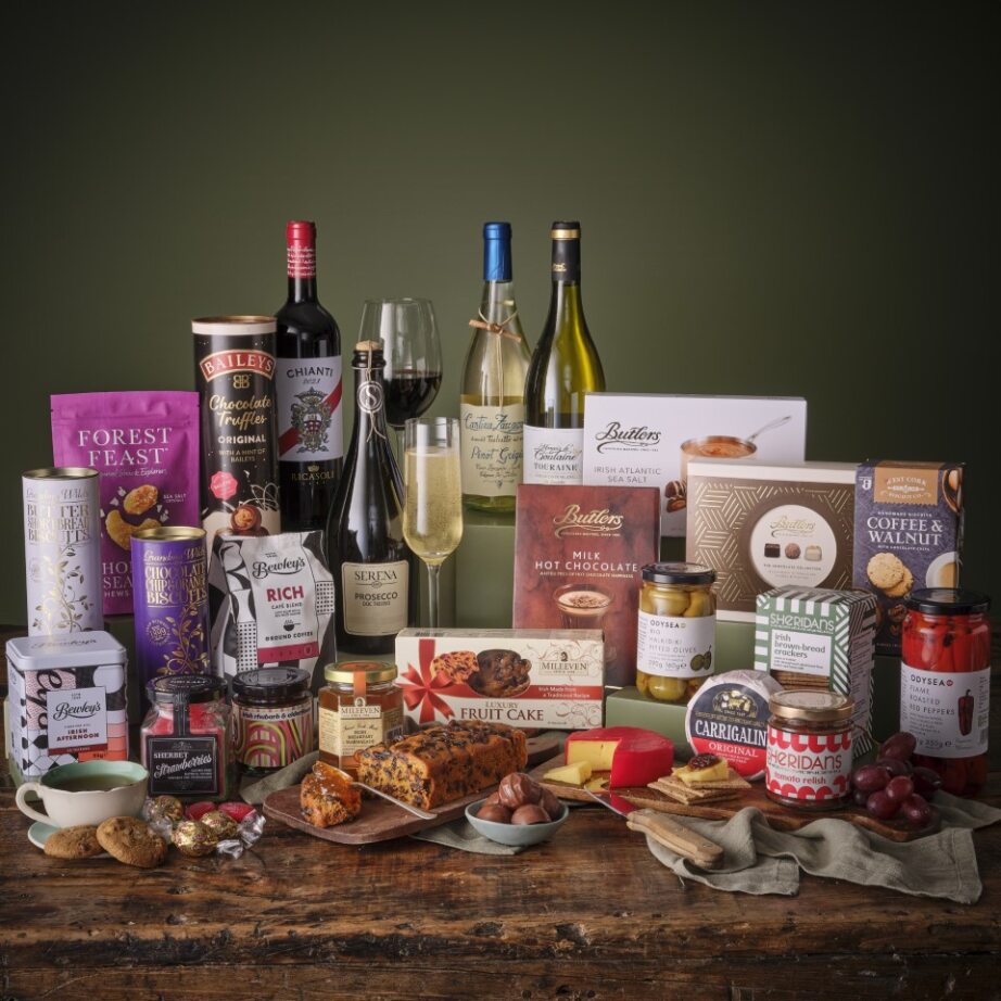 Assortment of gourmet items including wine bottles chocolates and jars arranged on a wooden table.