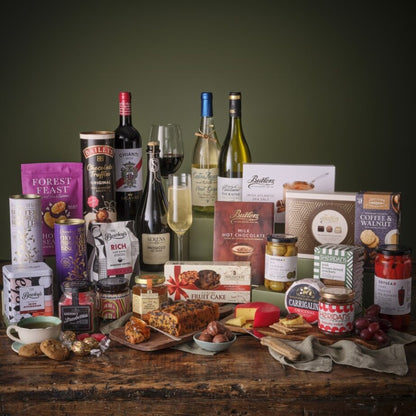 Assortment of gourmet items including wine bottles chocolates and jars arranged on a wooden table.