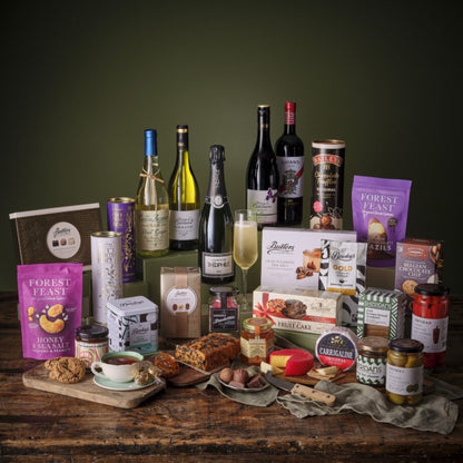 Deluxe hamper featuring wine bottles, chocolates and gourmet snacks arranged on a rustic wooden table.