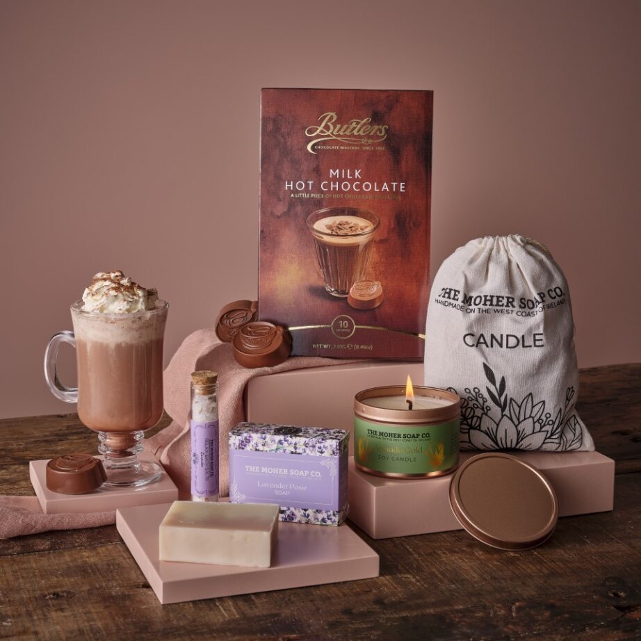 Time to Relax Hamper featuring hot chocolate lavender soap a candle and pampering items arranged on pink display blocks
