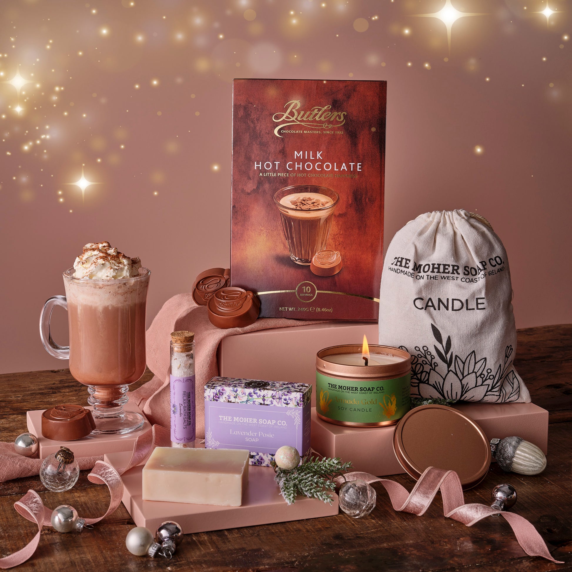 Butlers milk hot chocolate box, candle, soap, and decorative items on a wooden surface with a warm glow.