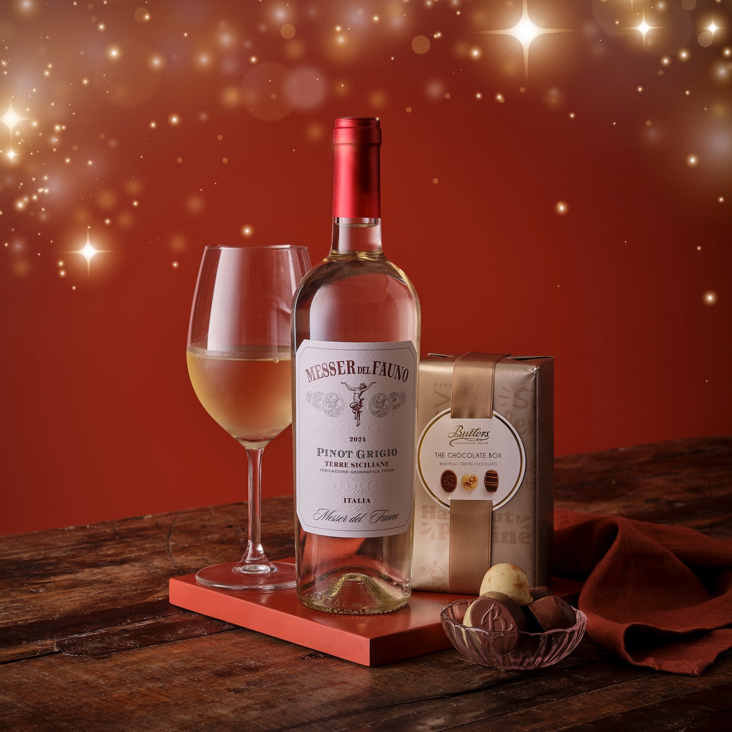 White Wine bottle, glass, and chocolate bar on a wooden surface with a warm glow background