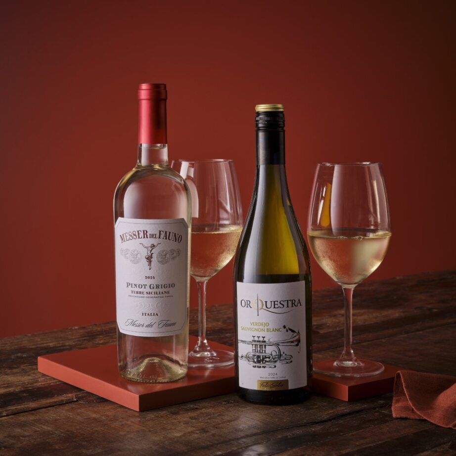 Two wine bottles with glasses on a wooden surface against a warm, glowing background