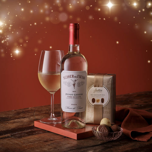 Wine bottle, glass, and chocolate box on a wooden surface with a warm background
