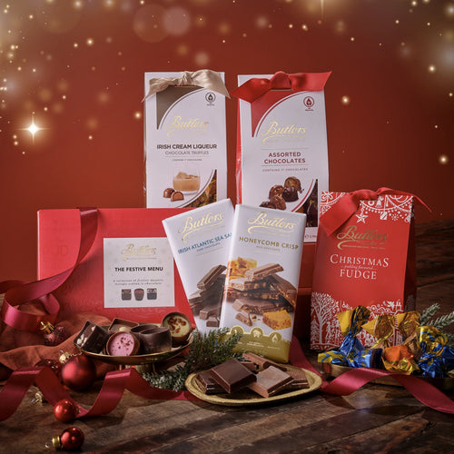Butlers chocolate products with festive decorations on a wooden table against a red background.