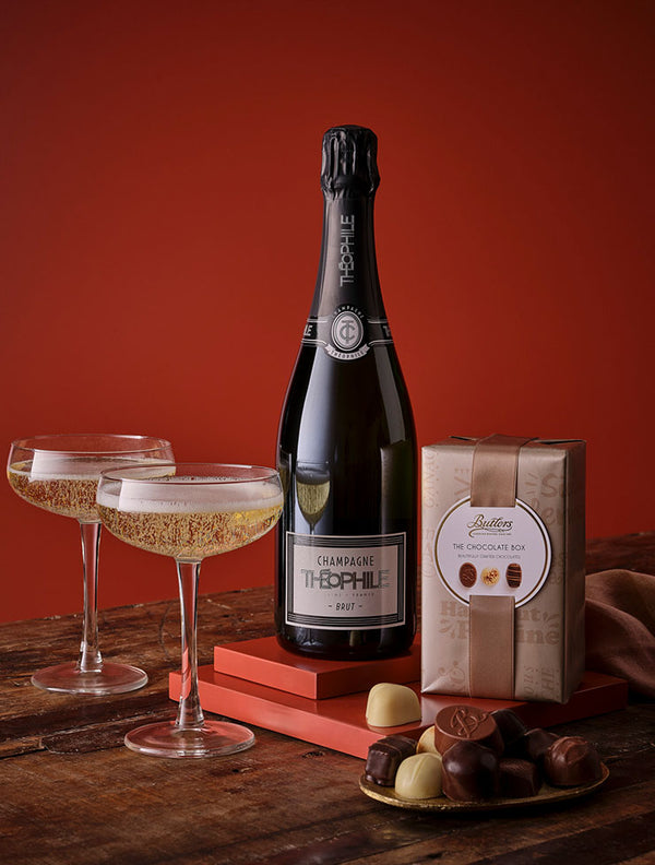 Champagne bottle and chocolates on a wooden table with decorative elements.
