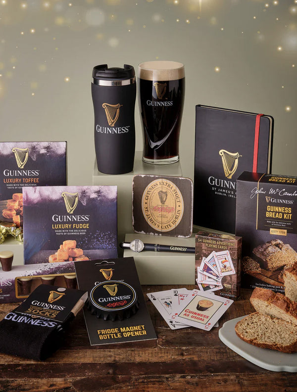 Collection of Guinness-themed products including a mug, toffee, fudge, and other items on a wooden surface.
