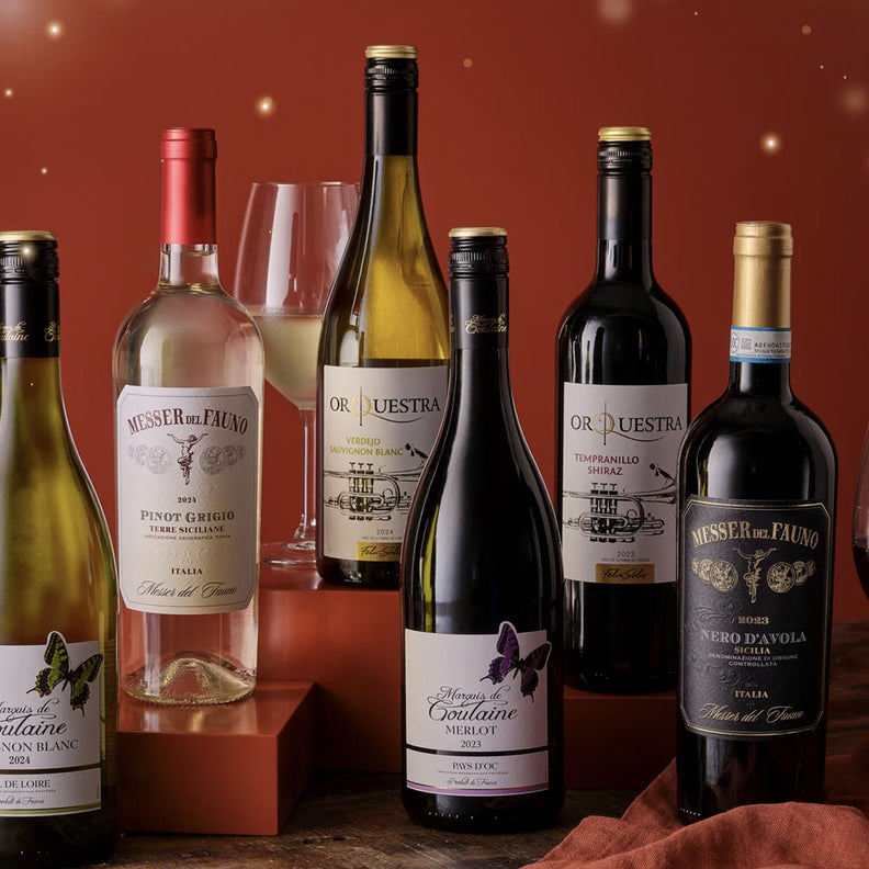 Assorted wine bottles and glasses on a wooden surface with a warm, glowing background.