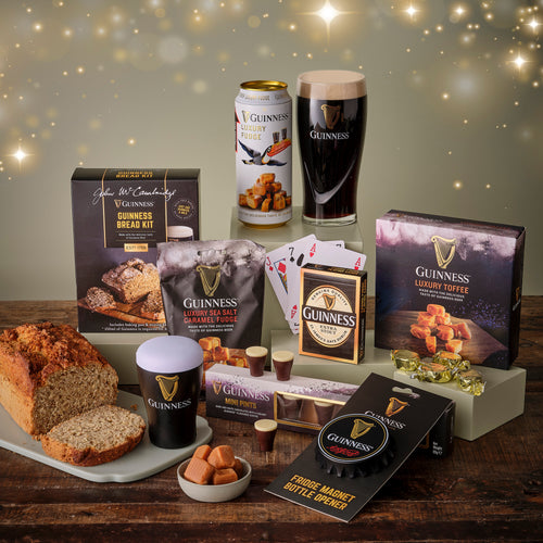 Collection of Guinness-themed products including beer, toffee, and snacks on a wooden table.
