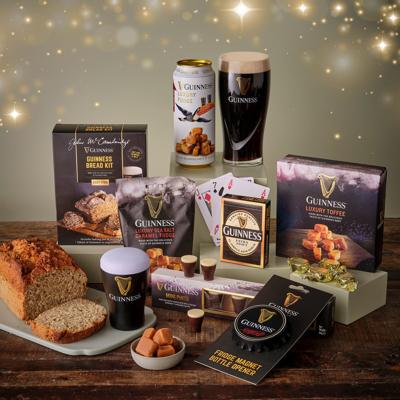 Collection of Guinness-themed products including beer, toffee, and snacks on a wooden table.