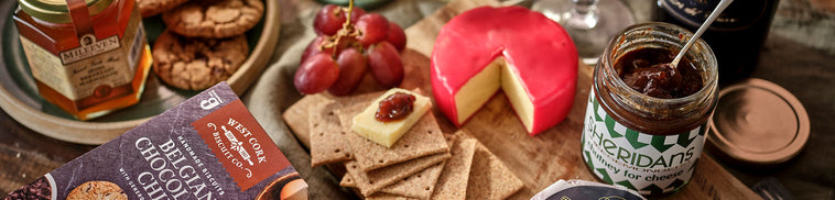 Assorted cheeses, crackers, and spreads on a wooden board with a rustic background.