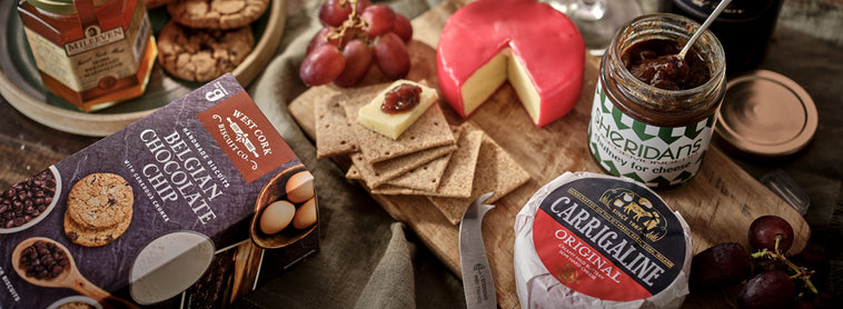 Assorted cheeses, crackers, and spreads on a wooden board with a rustic background.