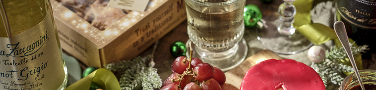 Wine bottle, glass, and fruit on a wooden table with a rustic background