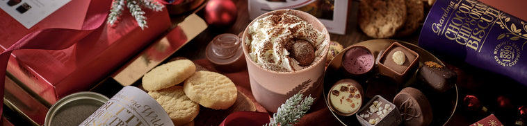 Assorted chocolates and cookies on a wooden table with a festive background