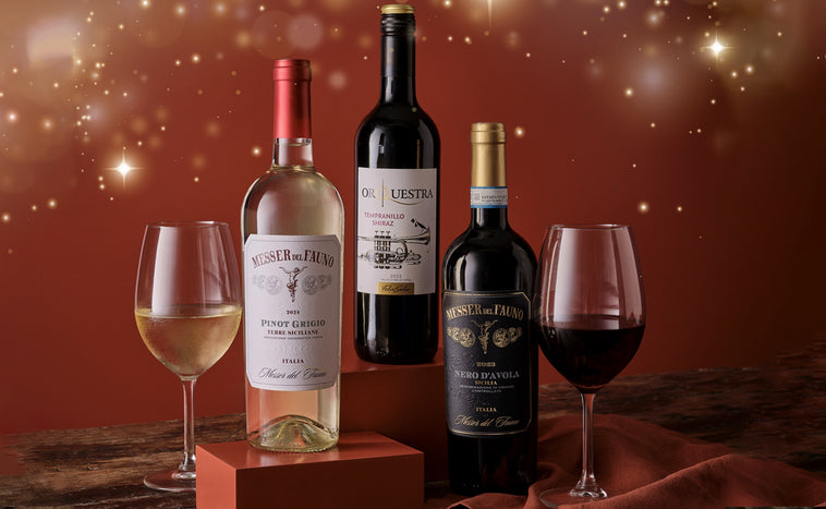 Three wine bottles and two glasses on a wooden surface with a warm, glowing background.