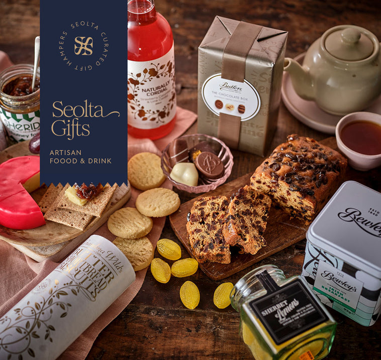 Assorted cheeses, crackers, treats and spreads on a wooden board with a rustic background. With Seolta Gifts branding in the corner.