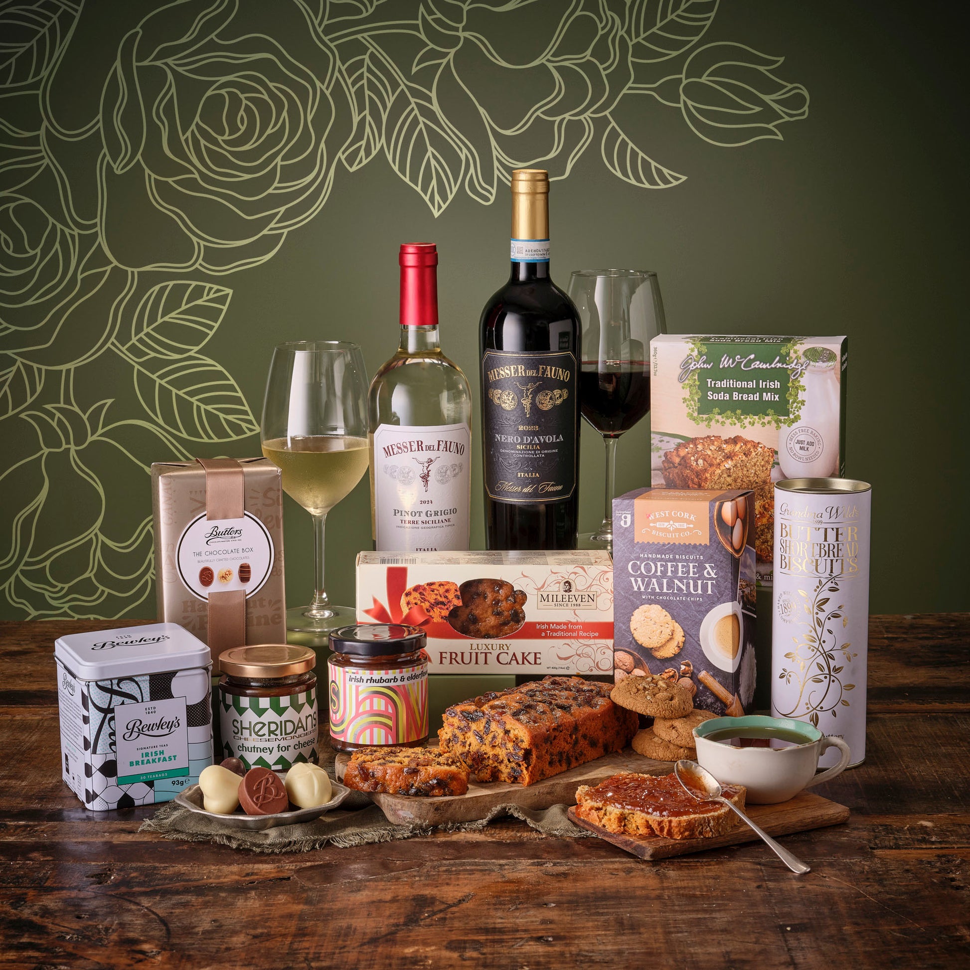 Thinking of Mum Hamper featuring chocolates biscuits hot chocolate and snacks arranged with wine in a cozy setup