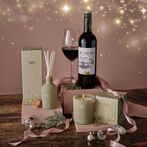 Wine bottle, candle, and diffuser on a wooden table with decorative elements.